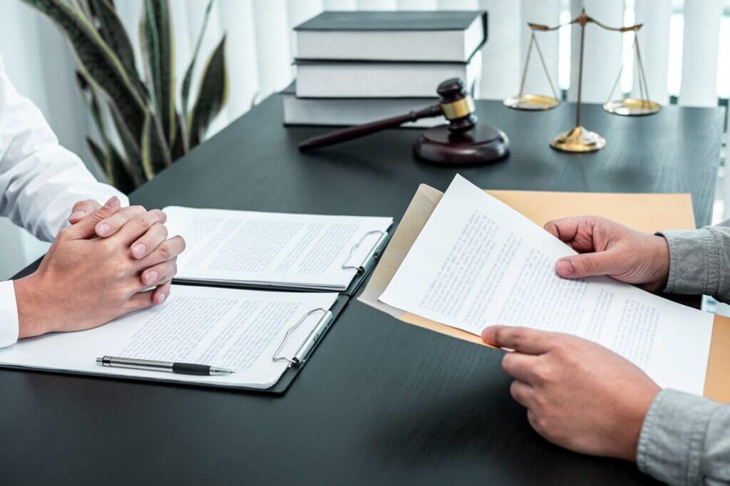 Male lawyer discussing negotiation legal case with client meeting with document contract in office