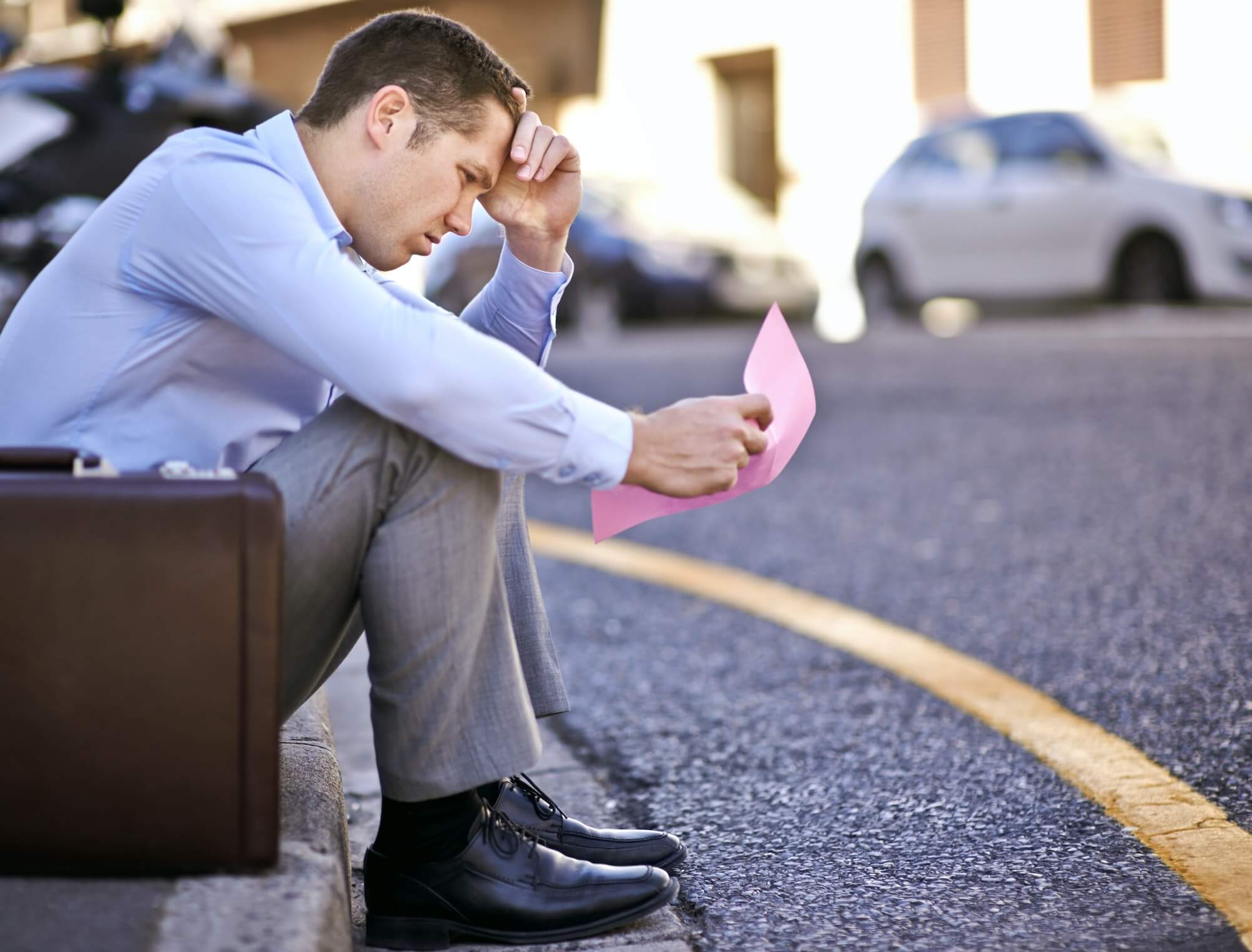 A businessman holding a pink slip terminating his employment